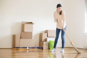 woman sweeping new home with moving boxes in the background