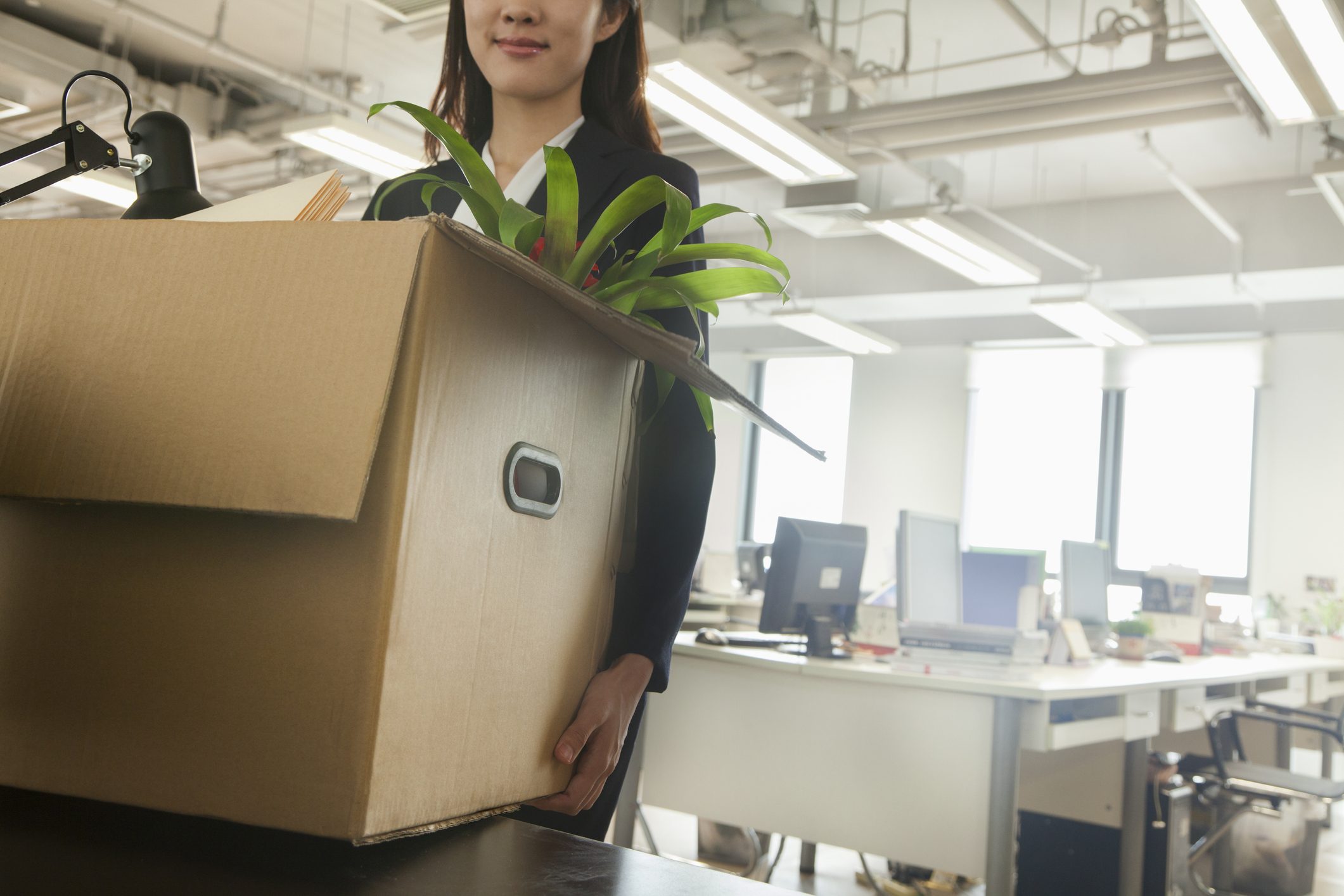 woman holding box in office with plant inside